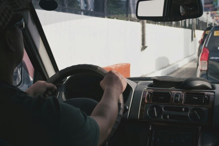 A driver's hands on the steering wheel, seen from inside a truck cab.