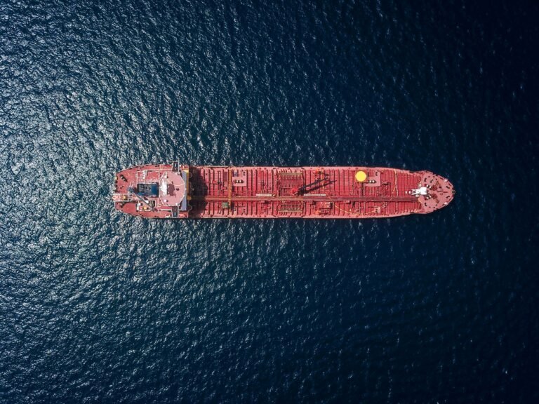 Aerial view of a red oil tanker ship on a dark blue sea.